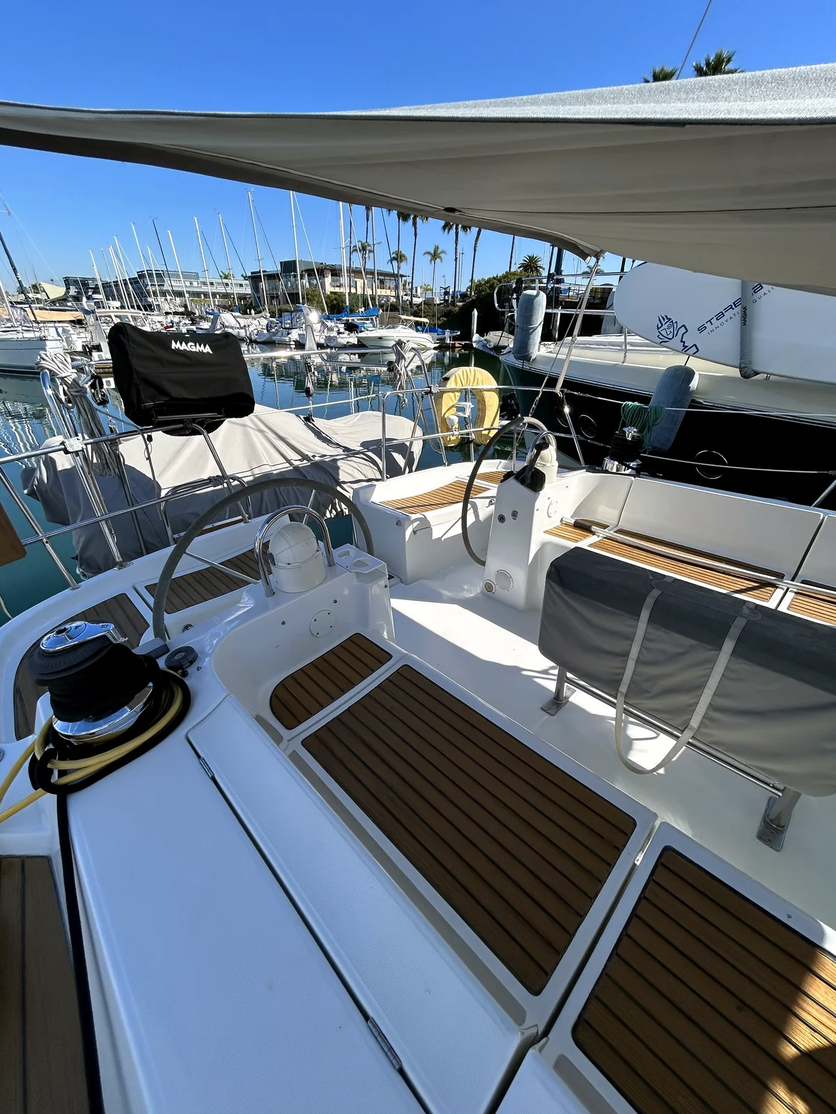 Sailboat cockpit and rigging at a San Diego marina with palm trees